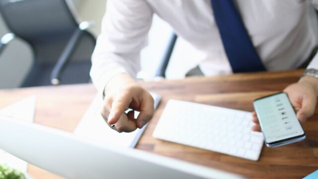 man at a computer with a smartphone