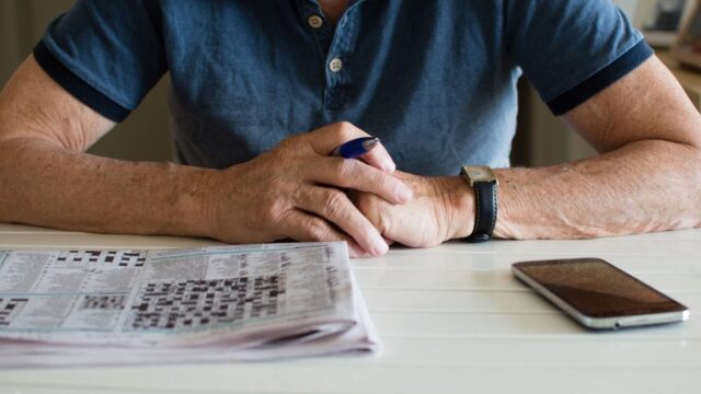 man with a newspaper, pen and smartphone