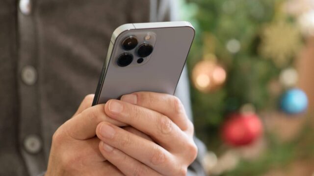 man holding iphone with christmas tree in background