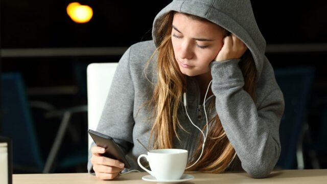 sad teen on phone in coffee shop